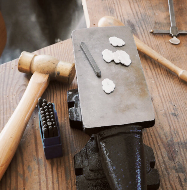 Workbench with hammer, stamps and metal cloud tokens.