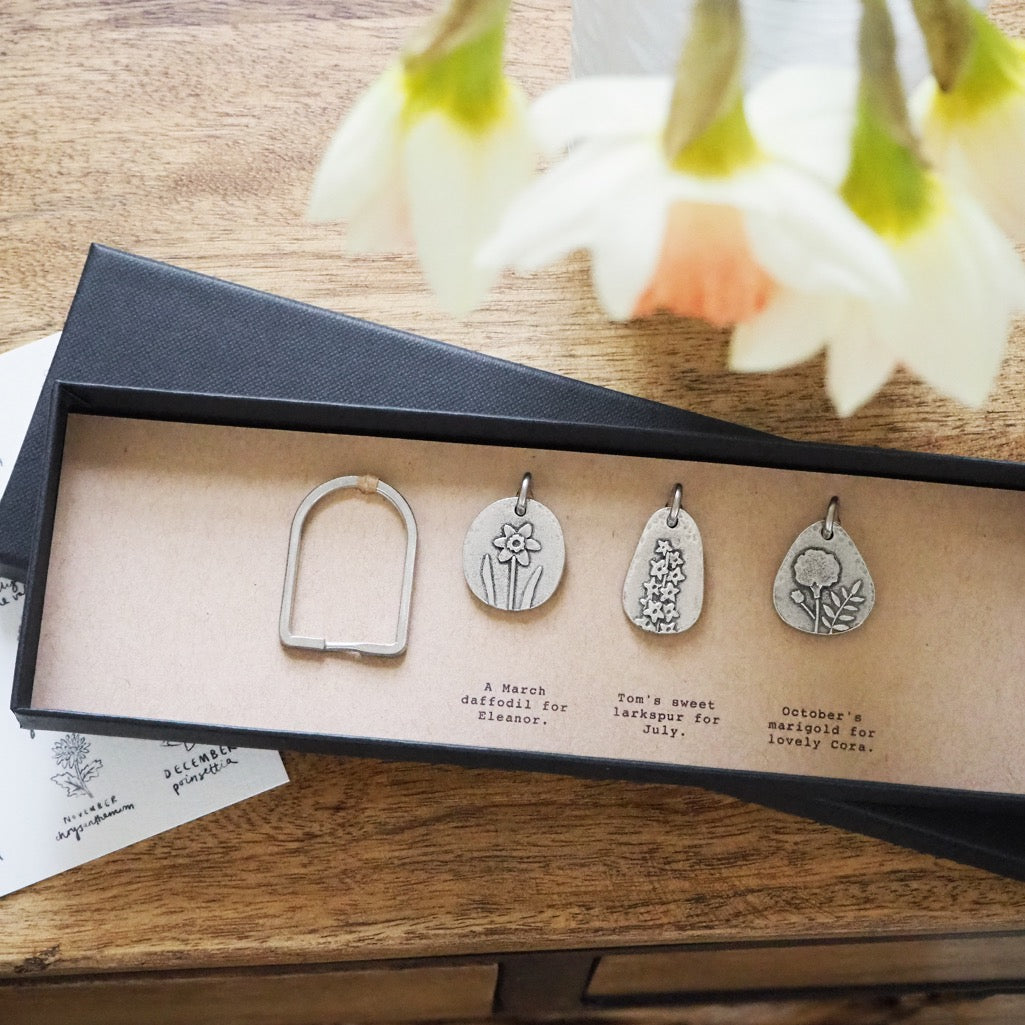 Three birth flower charms with a split ring in a long gift box.